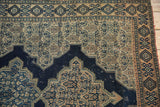 Worn navy scalloped medallion, intricate beige Herati field, geometric border on antique Senneh rug.
