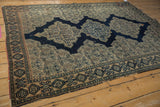 Antique Senneh rug corner detail, revealing intricate navy and ivory border with tattered edges.
