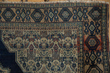 Antique Senneh rug's pale terracotta hexagonal motif, navy geometric patterns, worn beige field.