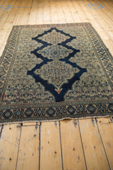 Tattered fringe, geometric border, and intricate ivory Herati motifs on the antique Senneh rug.