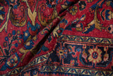 Folded vintage Lilihan rug detail: cherry red field, navy blue border, gold floral motifs.