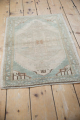 Lower edge of the vintage distressed Oushak rug, highlighting cream pile and narrow vined seafoam green border.