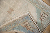 Folded vintage Oushak rug detail, showing distressed cream, seafoam, and brown pile with even wear.