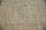 Faded ivory, dusty sage, and blush hues on the distressed pile of a vintage Oushak carpet.