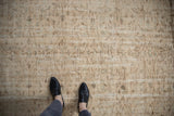 Distressed vintage Oushak carpet texture, showing faded cream, bronze, and seafoam green with feet.