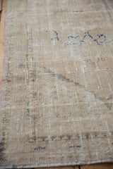 Close-up of distressed Oushak runner's muted cream and blue tones, knot head wear, intact selvage.