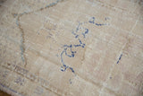 Distressed cream Oushak rug texture with faded navy and slate blue curvilinear motifs.