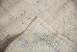 Distressed Oushak rug showing worn pile, exposed foundation, and intact side cord.