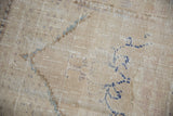 Distressed Oushak rug detail showing worn cream pile and faded blue patterns.