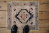 Distressed Oushak rug showing stepped navy medallion, pale blush field, and fine beige border.