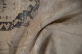 Distressed vintage Oushak rug's soft pile, folded, showing ivory and oxidized silver patterns.