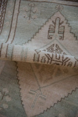 Distressed pile texture on a vintage Oushak rug's rolled edge, with pale ivory and seafoam patterns.