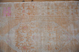 Exposed knot heads and pale tangerine floral motifs on a distressed vintage Oushak rug.