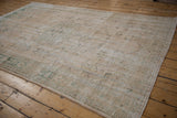 Heavily abrashed cream field with dusty sage border on a vintage Oushak rug.