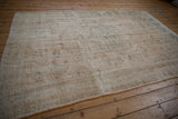 Distressed vintage Oushak rug section, featuring faded cream and soft jade green vinery.