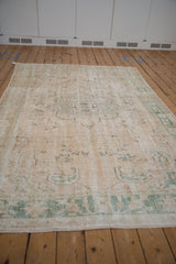 Distressed vintage Oushak rug pile, featuring faded cream, ivory, and dusty sage.
