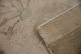Distressed Oushak rug pile with even wear, dusty ivory, and original side selvedge.