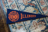 University of Illinois crest and lettering in orange on a vintage navy felt pennant.