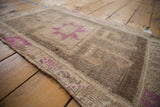 Distressed vintage Kars rug with fuchsia geometric starburst and hand-knotted abrashed texture.