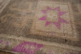 Hand-knotted distressed Kars rug pile with fuchsia geometric starburst and abrashed ground.