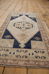 Vintage Oushak rug section showing distressed ivory field, navy geometric, and copper vine border.