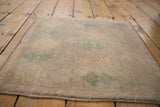 Distressed vintage Oushak rug, showing intact side selvage and green arrowed floral motif.