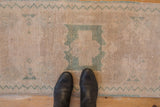 Distressed vintage Oushak runner with dusty seafoam green medallion and plant motifs.
