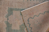 Distressed Oushak rug showing worn pile, woven foundation, and original side cord selvage.