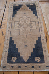 Distressed vintage Oushak rug with stepped geometric patterns in beige and dusty navy.
