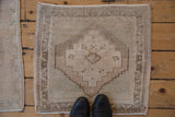 Distressed Oushak rug corner features worn low pile and subtle greige geometric patterns.