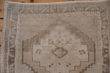 Vintage Oushak rug's stepped medallion, corner spandrel, and distressed texture in beige, greige.