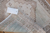 Hand-woven reverse, side cord selvage, and white tag on vintage distressed Oushak rug.