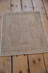 Angled view of a distressed Oushak mat, with even wear across its beige and ivory pile.