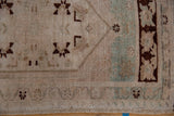 Vintage Oushak rug with abrashed beige field, celadon green, and chocolate floral border.