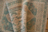 Distressed vintage Oushak rug's soft pile, featuring muted pale green turquoise and beige patterns.