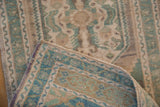 Distressed Oushak rug pile revealing abrashed pale green floral motifs and purple-edged selvage.