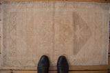 Distressed Oushak rug in muted beige, featuring abrashed field, faded medallion, and even wear.