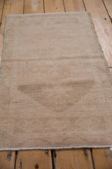 Vintage distressed Oushak mat featuring a subtle faded medallion on an abrashed field.