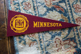 Yellow University of Minnesota school crest on the textured maroon felt of a vintage pennant.