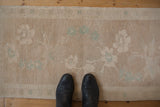 Distressed Oushak rug mat with soft, even wear and celadon green floral blossoms.
