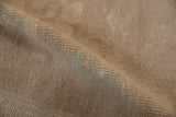 Close-up of the distressed pile revealing the hand-knotted texture in sand and celadon green.