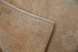 Back of a distressed Oushak rug showing the hand-knotted foundation and original side selvage.
