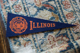 The orange school crest and 1867 date on the navy blue vintage felt pennant.