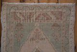 Distressed vintage Oushak rug pile, featuring cream and celadon stepped patterns.