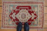 Distressed Oushak rug corner, showing cherry red wave border and pale turquoise field patterns.