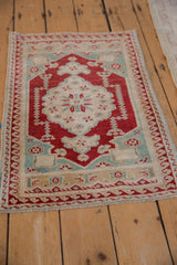 Distressed Oushak rug corner showing cherry red reciprocating wave border and fringe.