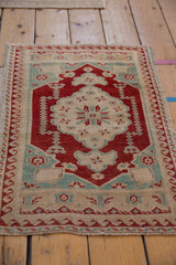 Distressed Oushak rug with cherry red roundel, seeded designs, and wave border.