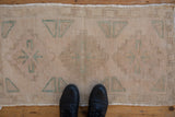 Distressed vintage Oushak rug mat shown on the floor for scale, highlighting its soft, evenly worn pile.