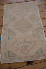 Angled view of the distressed Oushak mat, highlighting its even wear and faded motifs.