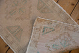 A folded corner on the distressed Oushak rug reveals its low pile and hand-knotted reverse.